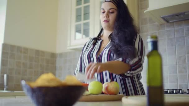 Mollig meisje is koken in de keuken — Stockvideo