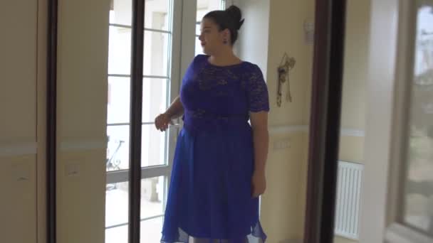 Толстая девушка в синем платье перед зеркалом — стоковое видео