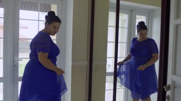 Товста дівчина в блакитній сукні перед дзеркалом — стокове відео