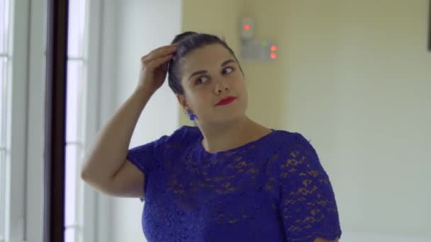 Толстая девушка в синем платье перед зеркалом — стоковое видео