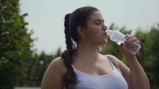 Dik meisje drinkt water uit een fles — Stockvideo