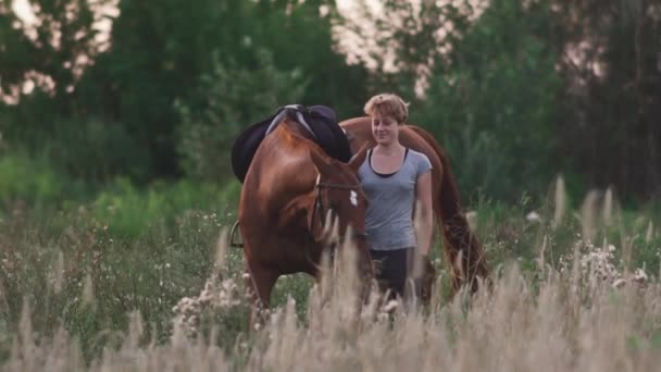 Jovem está segurando o cavalo para as rédeas — Vídeo de Stock