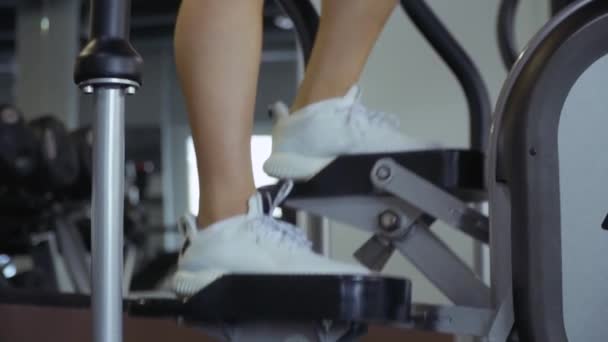 Belle jeune fille sur le simulateur dans la salle de gym — Video