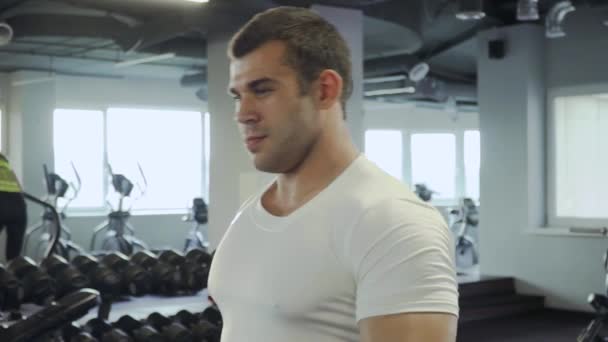 Bonito cara fazendo exercícios com halteres no ginásio — Vídeo de Stock