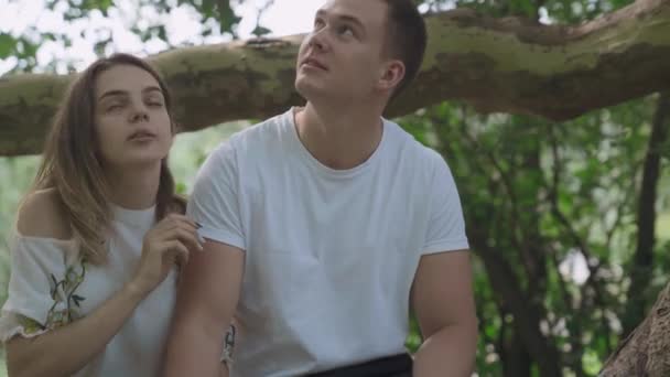 Ung man och kvinna sitter i trädgården — Stockvideo