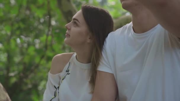 Young man and woman is sitting in the garden — Stock Video