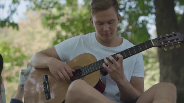Молодой парень играет на улице на гитаре — стоковое видео