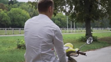 İyi biri onu takip etmeye davet ediyor. Yakışıklı olan bir işareti yapmak. Genç adam bir motosiklet Binme. Kamera ve gülümsüyor yakışıklı adamın.