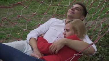 Adam bir kız bir hamakta sarılmak. Ön plan üzerinde sarı retro moped.