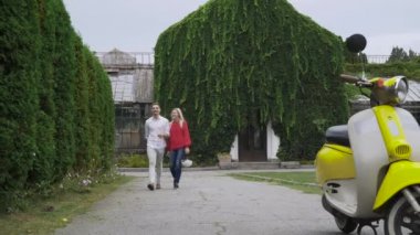 Adam ve kız kask tutun ve scooter için gidin. Genç bir çift bir scooter sürme. Bir motosiklet sürme.