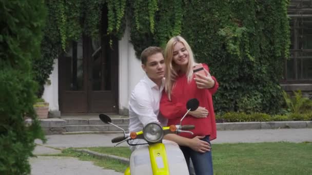 情侣在摩托车附近做自拍 一辆轻便摩托车的家伙抱着一个女孩 一个女孩和一个男人在打电话 — 图库视频影像