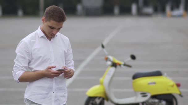Jovem Está Lado Uma Scooter Bonito Tipo Camisa Branca — Vídeo de Stock