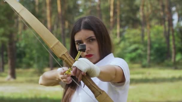 女孩弓箭手在目标和芽之间移动弓 女射手瞄准她的弓对准目标 女性鲍曼射击目标与她的弓和箭 — 图库视频影像
