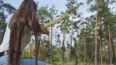 Pruvadan oturma konumu ile çekim kız. Bayan archer başlatılması ok ve dize geri gökyüzüne doğru çizin. Bayan archer onun yay hedefe matuf. Bayan bowman hedef onun yay ile çekim