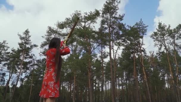 Девушка в красном платье выпустила стрелу в небо — стоковое видео