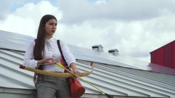 Chica joven apunta con un arco en el techo de una casa — Vídeos de Stock