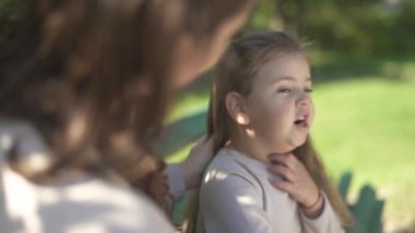 Anne ve küçük kızı parkta bir bankta oturan