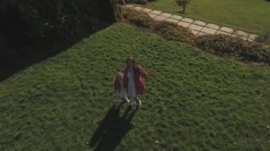 Küçük kız ve annesi eller dalga ve kamera için hava öpücük göndermek. Aile mutludur. Anne ve sarışın kız birlikte vakit. Anne ve çocuk ilişkisi var. Kamera hamle