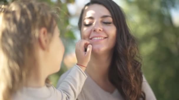 Kis lány pets arc anyja a parkban — Stock videók