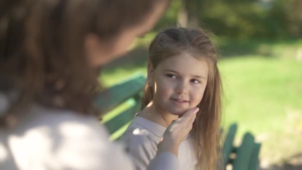 Madre mascotas cara de su hija en el parque — Vídeo de stock