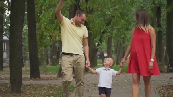 Les parents tiennent les garçons par la main et marchent dans le parc — Video