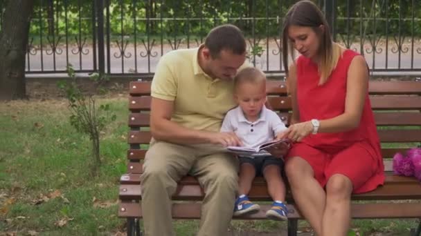 Jonge ouders tonen een jonge zoon een boek — Stockvideo