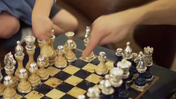 Händerna på en liten pojke ordna om schack på ett schackbräde — Stockvideo