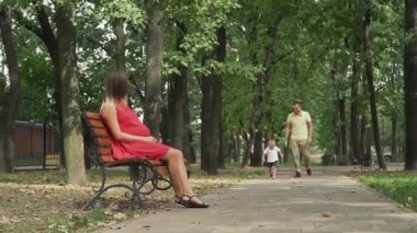 Parkta bir bankta oturan anne küçük çocuk çalışır