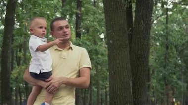 Baba bebek onun kollarında tutar.