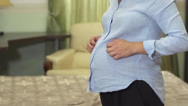 Těhotná žena je hladil její břicho a popíjel v pokoji — Stock video