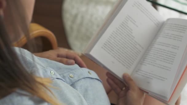 Έγκυος γυναίκα κάθεται σε μια καρέκλα και διαβάζει ένα βιβλίο. — Αρχείο Βίντεο