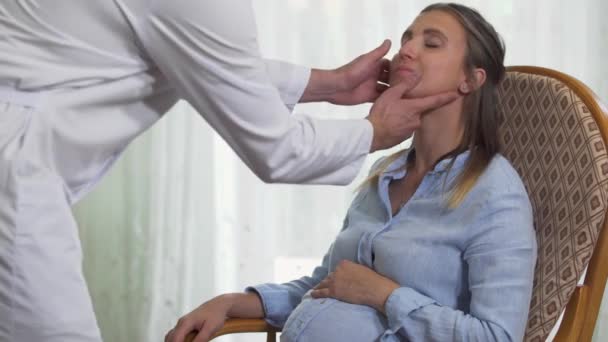 El médico mira la garganta de una mujer embarazada — Vídeo de stock