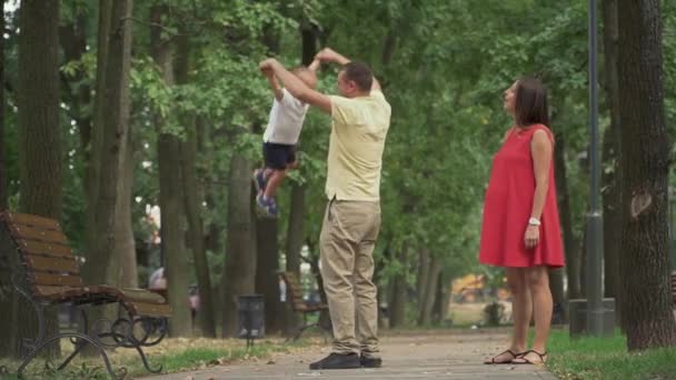 Папа обходит своего маленького сына по кругу в парке — стоковое видео