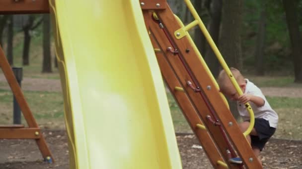 Schöner kleiner Junge erklimmt die Rutsche — Stockvideo