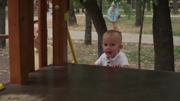 Ребенок забирается на детскую горку в парке — стоковое видео