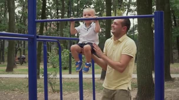 Vater zieht seinen kleinen Sohn an der Querstange hoch — Stockvideo