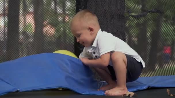 Barn som sitter på språngbräda drar ut en ballong — Stockvideo