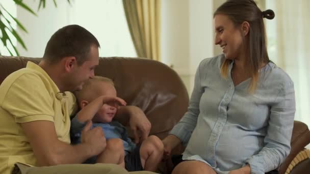 Νέοι γονείς και ο μικρός γιος στον καναπέ μαζί — Αρχείο Βίντεο