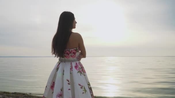Brunette in lange jurk staande door de rivier — Stockvideo