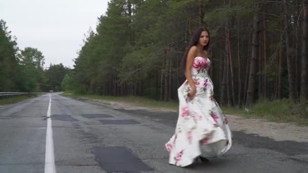 Chica joven en un vestido largo y hermoso camina al aire libre — Vídeo de stock