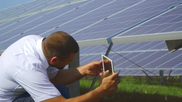 Мужчина фотографирует заднюю часть солнечной панели — стоковое видео