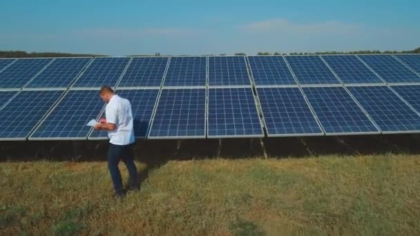 Mitarbeiter machen sich in der Nähe der Solarzellen Notizen. Schuss auf Drohne — Stockvideo