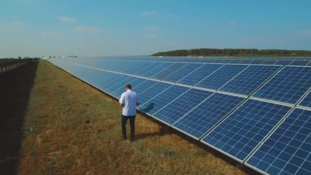 Hombre comprobando paneles fotovoltaicos. Disparo en dron — Vídeo de stock