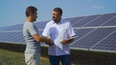 Güneş hücreleri arka plan üzerinde el sıkışan iki iş adamları