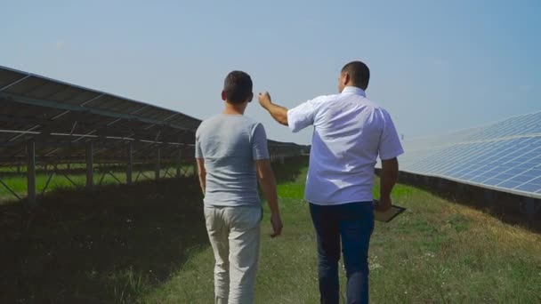 Два Бизнесмена Ходят Рядами Солнечных Батарей Генерация Чистой Возобновляемой Солнечной — стоковое видео