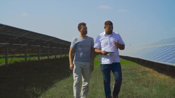 Twee zakenlieden wandeling in de buurt van de zonnepanelen. — Stockvideo