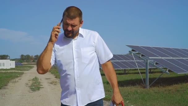 태양 전지 패널의 배경에 전화 통화 하는 남자 — 비디오