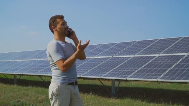 Zakenman praten aan de telefoon op het veld met zonnepanelen — Stockvideo