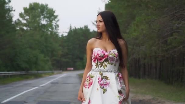 Hermosa chica en un vestido largo camina en el camino — Vídeos de Stock