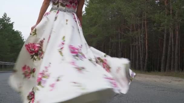 Menina macia em um vestido longo está girando na estrada — Vídeo de Stock